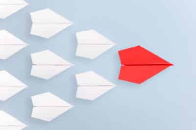 A formation of paper planes with a red leader, to show a brand influences and leads others in a blog by Joanne Tan, business branding expert,10PlusBrand.com